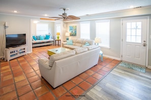 Relax in this stylish living room with a large sofa, flat-screen TV, and ceiling fan.