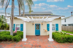 Stroll under the shaded pergola, surrounded by a charming brick pathway and a whimsical touch of flamingo statues.