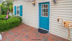 A house with a blue door, a pink flamingo, and a white flamingo statue.