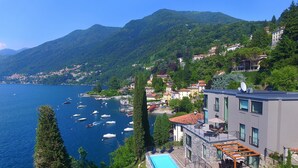 A hillside property with a swimming pool, overlooking a lake with boats.