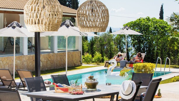 An outdoor pool area with lounge chairs, umbrellas, and a dining table with chairs. - Villa Grande Casa with Pool, Villa Grande Casa with Swimming Pool (Corfu)