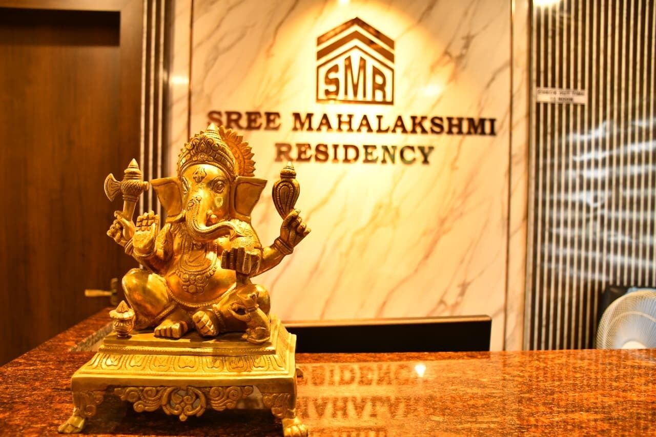 A golden statue of a deity on a marble pedestal in front of a sign for Sree Mahalaksmi Residency.