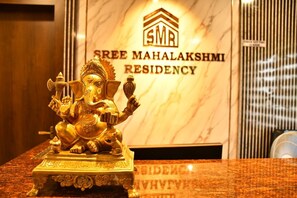 Une statue dorée d’une divinité, posée sur un piédestal de marbre, devant une enseigne indiquant « Sree Mahalaksmi Residency ».