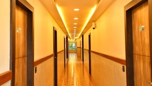 A hotel hallway with wooden doors, a patterned floor, and recessed lighting. - Sree Mahalakshmi Residency (Kariyapatti)