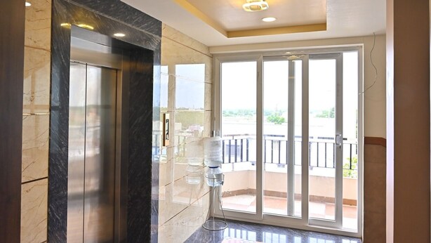 A modern interior with a glass elevator, a large sliding glass door leading to a balcony, and a ceiling with recessed lighting. - Sree Mahalakshmi Residency (Kariyapatti)