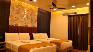 A hotel room with two beds, a patterned wall, a ceiling fan, and an air conditioning unit. - Sree Mahalakshmi Residency (Kariyapatti)