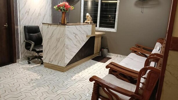 Zona de recepción con mostrador de mármol, una silla de oficina negra y sillas de madera.