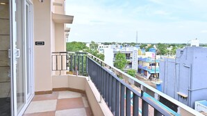 A balcony with a view of a cityscape, a door, and a small outdoor area with a railing. - Sree Mahalakshmi Residency (Kariyapatti)