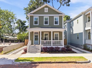 A two-story house with a front porch, a small front yard, and a neighboring house.