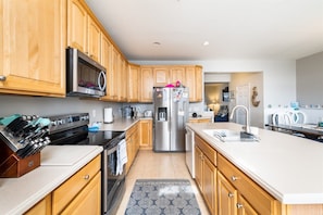 A modern kitchen with wooden cabinets, stainless steel appliances, and a central island. - Mini Weeks Stays Available Sunset Island 39 Island (Ocean City)