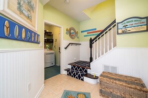 A staircase with a patterned handrail and a wicker bench at the bottom. - Mini Weeks Stays Available Sunset Island 39 Island (Ocean City)