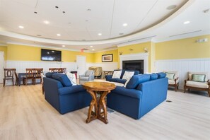 A hotel lobby with a curved ceiling, blue sofas, a wooden coffee table, and a fireplace.