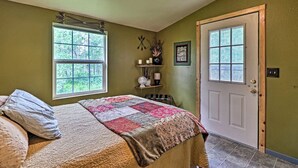 A bedroom with a bed, a door, and a window. - Duck Lake Cabin Rental Near GNP (Babb)