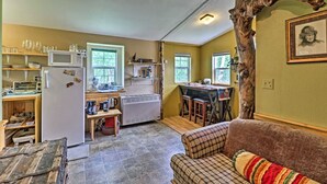 A compact kitchen with a refrigerator, microwave, and a dining area with a table and chairs. - Duck Lake Cabin Rental Near GNP (Babb)