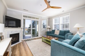 Un salon avec une cheminée, un téléviseur et un ventilateur de plafond.