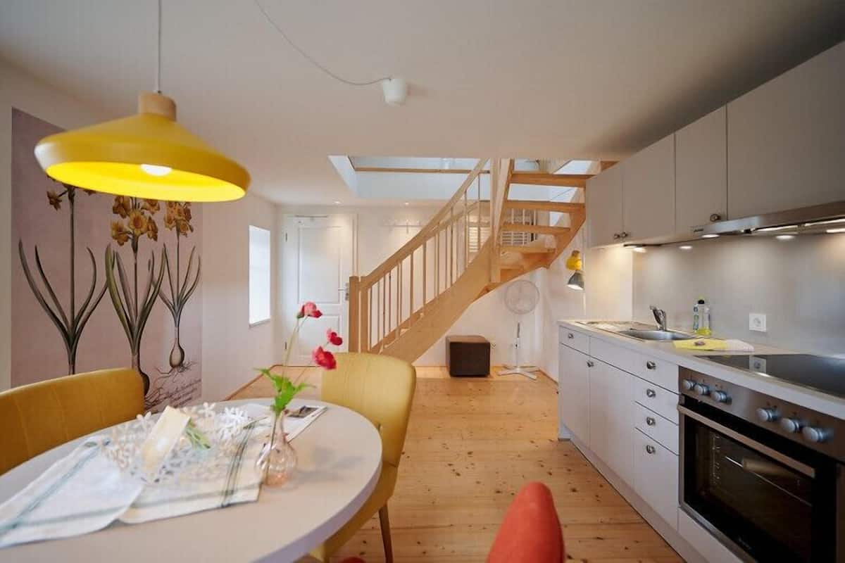 Een moderne keuken met houten vloeren, een inbouwoven en een trap naar een hoger niveau.