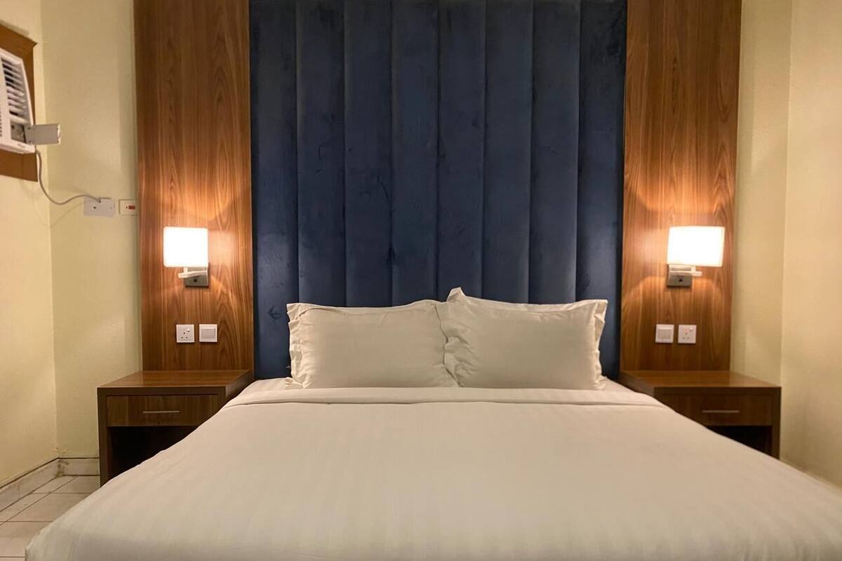 A hotel room with a large bed, two bedside tables, and a wooden headboard.