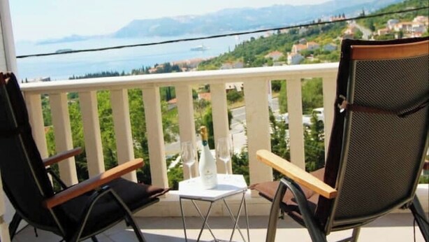 Ein Balkon mit zwei Stühlen, einem kleinen Tisch und einer Champagnerflasche.
