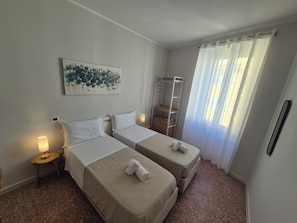 A hotel room with two beds, a bedside table with a lamp, a wardrobe, and a painting on the wall. - A casa di Alex Vatican (Rome)
