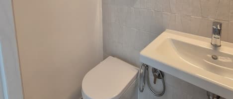 A modern bathroom with a toilet, sink, and mirror.