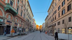 A wide, paved street lined with historic buildings, featuring a tram track down the center. - ALEX B&B (Rome)