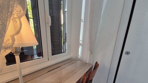 A dining area with a wooden table and chairs, a lamp, and a window with blinds. - ALEX B&B (Rome)