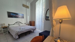 A hotel room with a bed, a desk with a lamp, a chair, a nightstand, a wardrobe, and a window with curtains. - ALEX B&B (Rome)