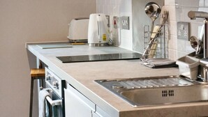Une cuisine moderne équipée d’un évier en acier inoxydable, d’une bouilloire, d’un grille-pain et d’un égouttoir à vaisselle.