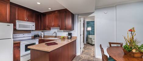 A modern kitchen with dark wood cabinets, a white microwave, and a large island.