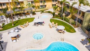A hotel pool area with sun loungers, a central pool, and surrounding greenery. - Winners Circle Solana Beach Del Mar Resort (Solana Beach)