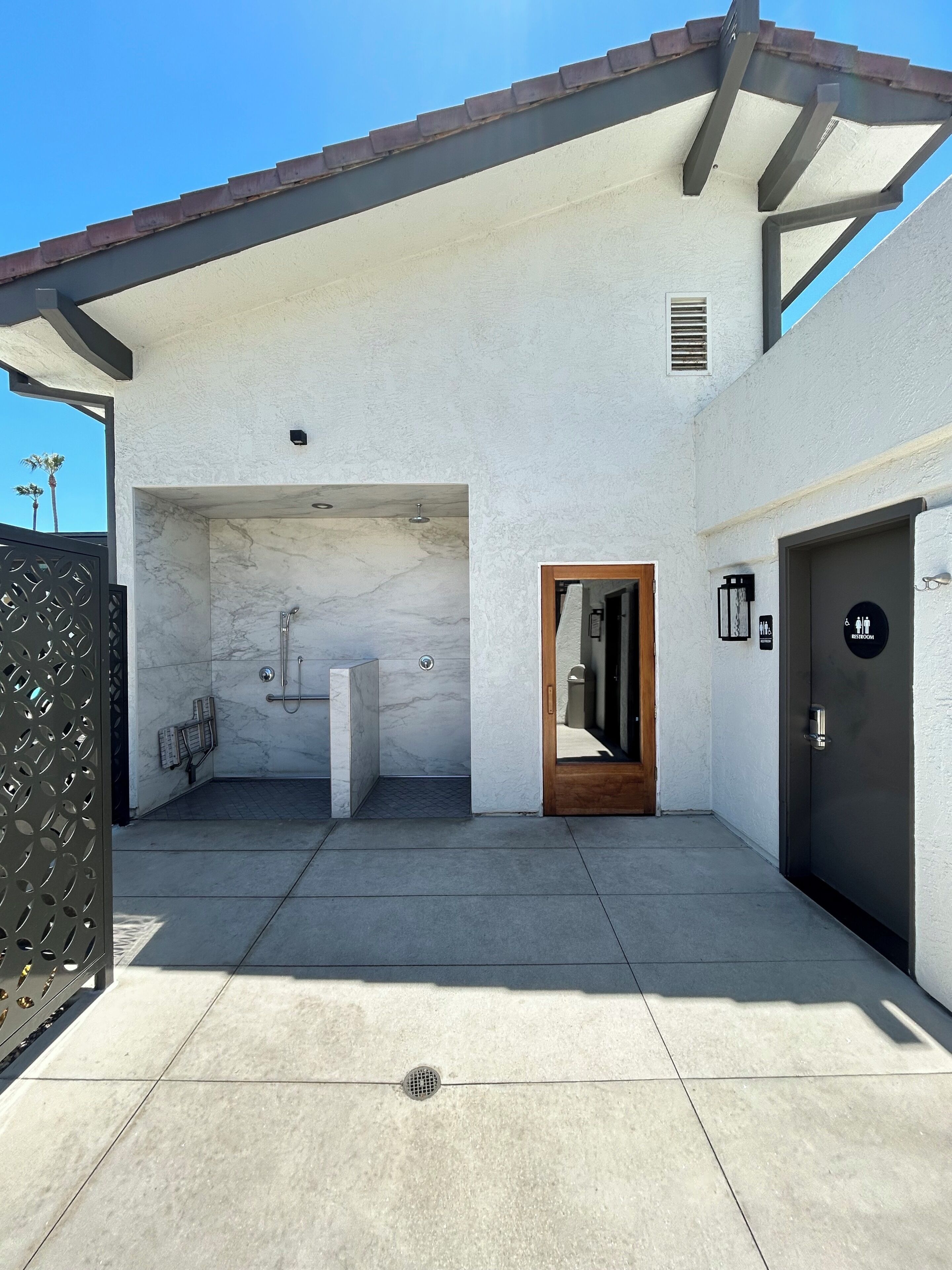 A modern building with a covered outdoor area, a marble shower, and a door labeled 'Restroom.'