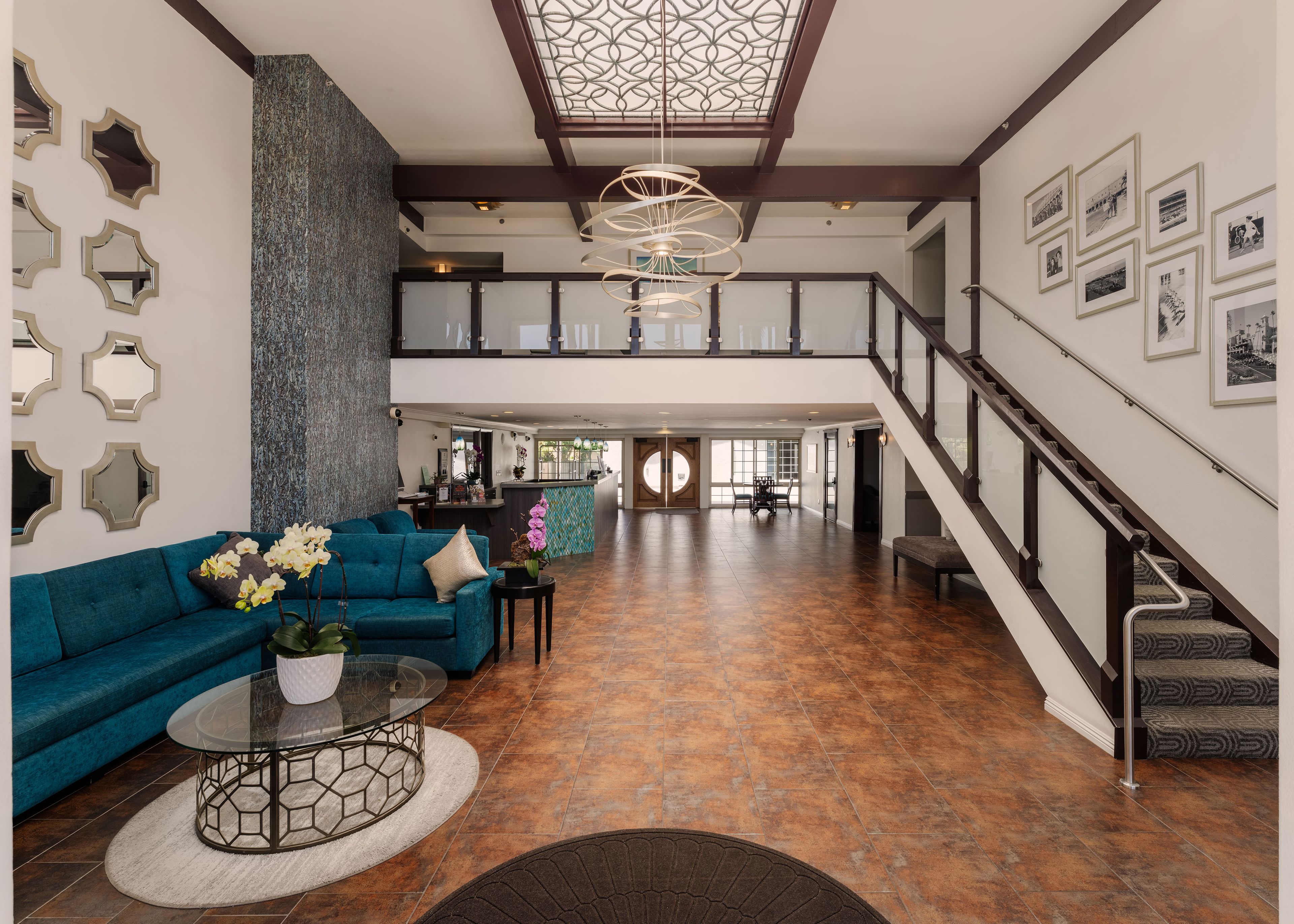 A spacious living area with a teal sofa, a glass coffee table, and a decorative ceiling light.