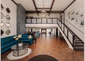 A spacious living area with a teal sofa, a glass coffee table, and a decorative ceiling light. - Winners Circle Solana Beach Del Mar Resort (Solana Beach)