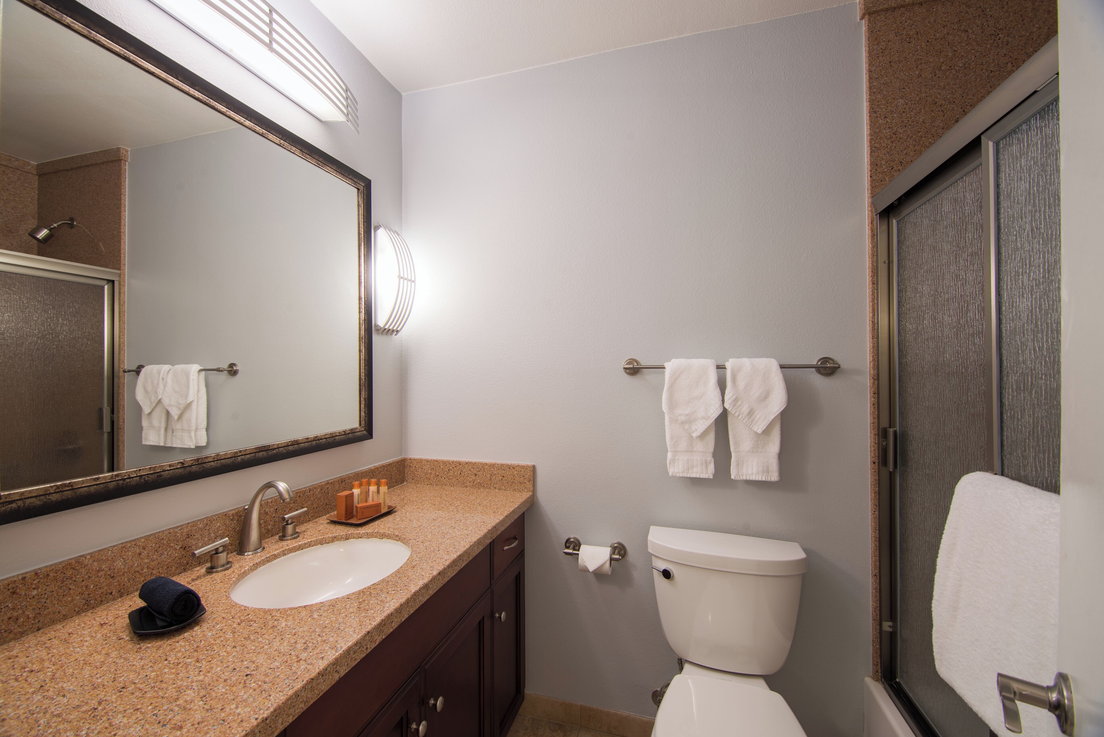 A bathroom with a sink, mirror, toilet, and towel rack.