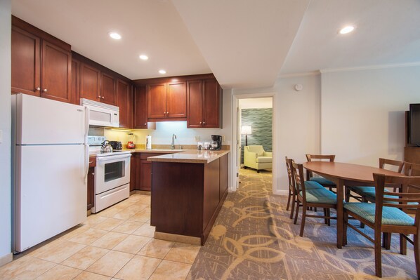 A modern kitchen with wooden cabinets, a white refrigerator, and a built-in oven. - Winners Circle Solana Beach Del Mar Resort (Solana Beach)
