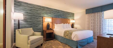 A hotel room with a bed, two bedside lamps, a chair, a nightstand, and a desk.