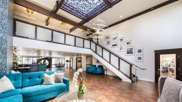 A spacious living area with a blue sofa, a glass coffee table, and a staircase leading to an upper level. - Winners Circle Solana Beach Del Mar Resort (Solana Beach)