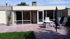 Una casa moderna con patio, puertas corredizas de vidrio y mobiliario exterior.