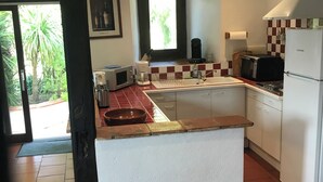 A kitchen with a central island, white cabinets, a microwave, a coffee maker, and a refrigerator. - Gîte with swimming pool in the Gers, 45 minutes from Toulouse.  (Gimont)