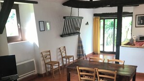A dining area with a wooden table and chairs, a television, and a view of the outdoors through a window. - Gîte with swimming pool in the Gers, 45 minutes from Toulouse.  (Gimont)