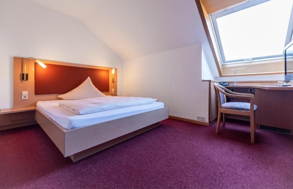 Une chambre d’hôtel avec un lit, un bureau et une chaise.
