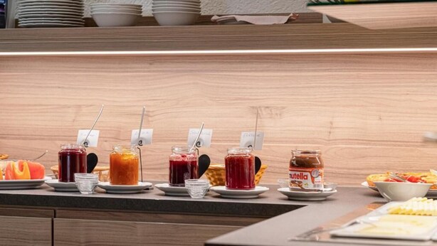 A buffet counter with various food items and condiments. - Hotel Phönix garni (Rastatt)