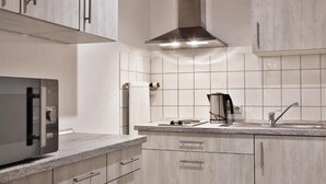 A modern kitchen with a built-in microwave, stove, and sink. - Hotel Phönix garni (Rastatt)