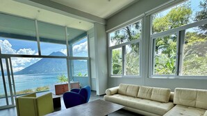 A modern living room with a large window overlooking a scenic view of a lake and mountains.