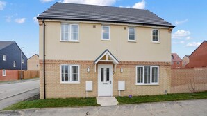 A two-story residential building with a beige facade, a dark roof, and a small front porch. - Broads Escape/ - 3 Bedroom House in Oulton Broads (Lowestoft)
