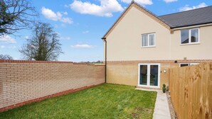 A two-story house with a brick exterior, a small front yard, and a wooden fence. - Broads Escape/ - 3 Bedroom House in Oulton Broads (Lowestoft)