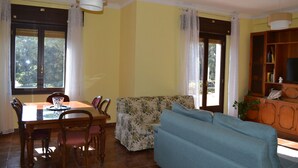 A dining area with a wooden table and chairs, a floral sofa, and a cabinet with books. - Cozy apartment a stone's throw from the historic center of Rome (Roma)