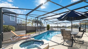 A covered outdoor swimming pool with lounge chairs and a hot tub.