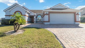A residential house with a garage, a well-maintained lawn, and a clear sky.
