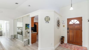 A spacious hallway with a wooden floor, a glass partition, and a wooden door.